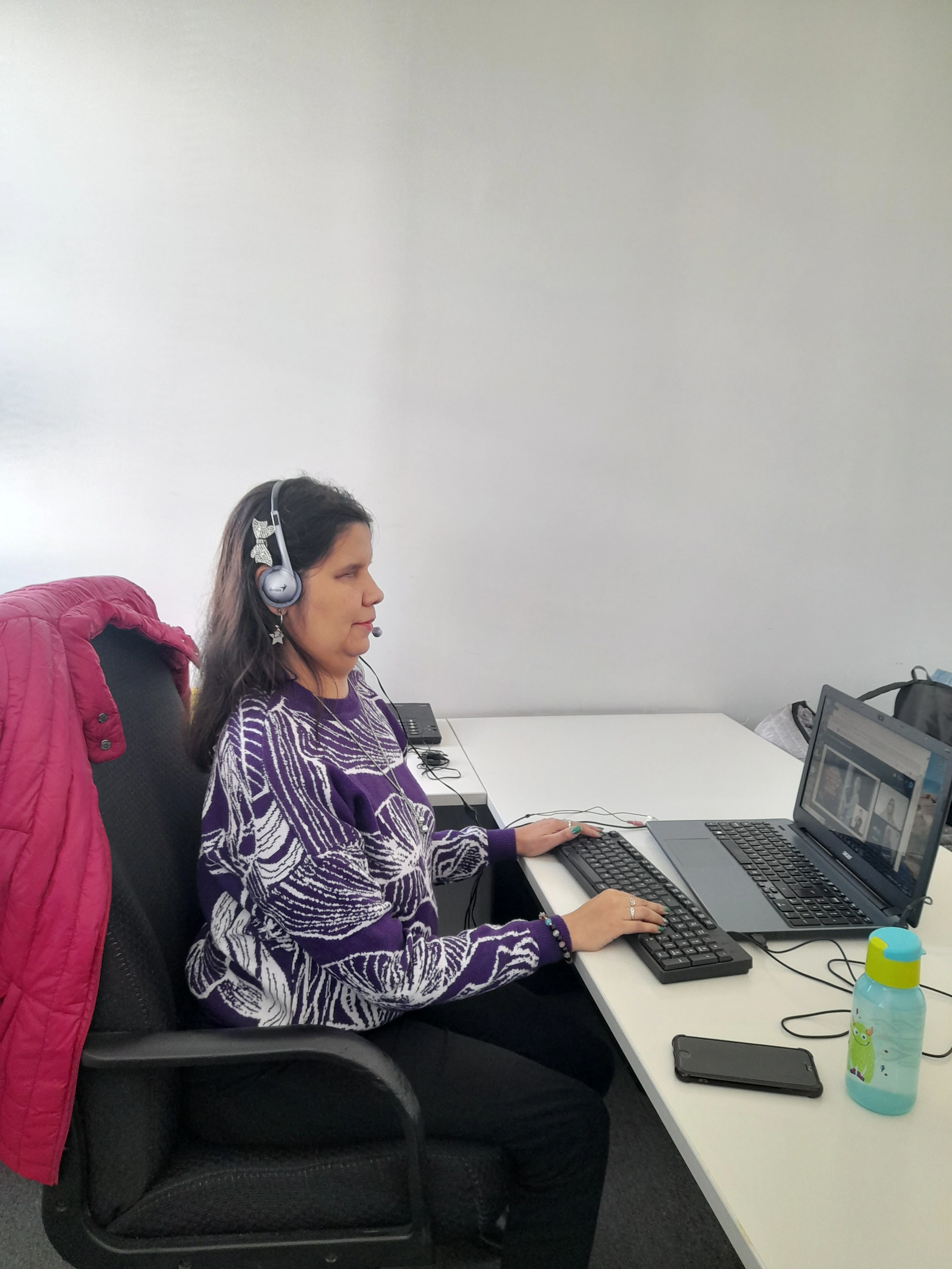 La coordinadora del programa ágora Lucía Torres  sentada en un escritorio utilizando un teclado y una computadora portátil durante la capacitación."